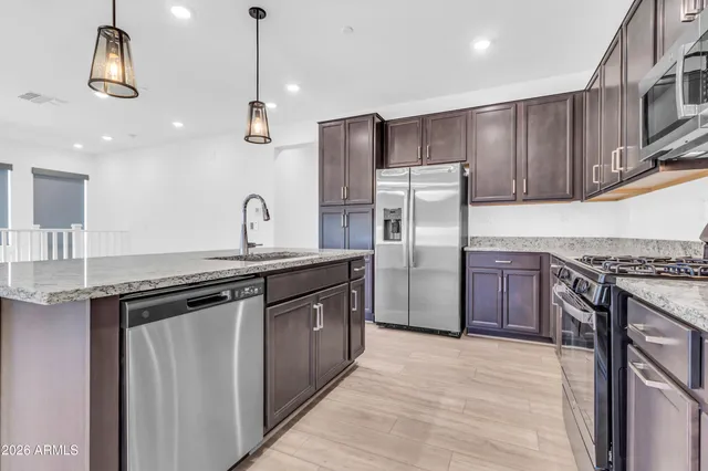 a kitchen with stainless steel appliances granite countertop a sink a stove a refrigerator and island with wooden floor