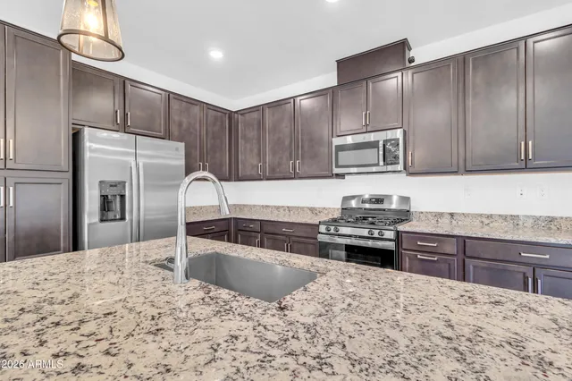 a kitchen with granite countertop a stove refrigerator and microwave
