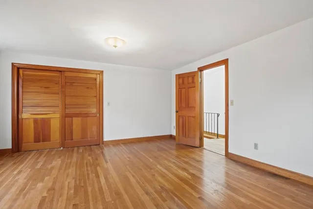 an empty room with wooden floor and closet area