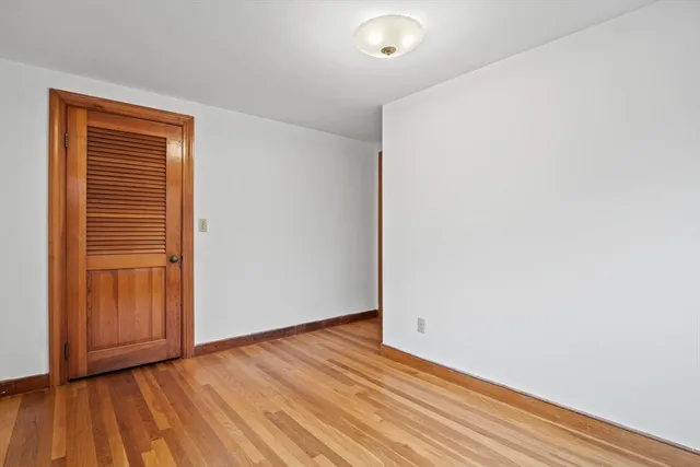 a view of an empty room with wooden floor and closet