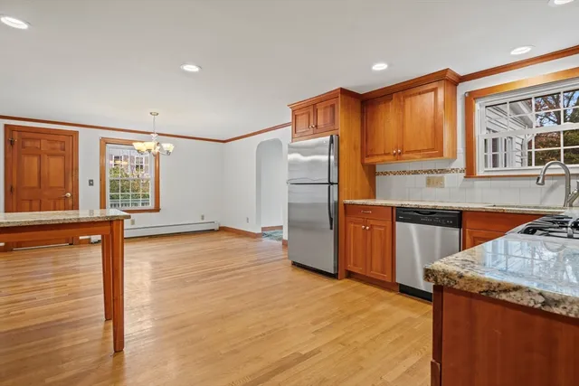 a kitchen with stainless steel appliances granite countertop a refrigerator a sink dishwasher and wooden cabinets with wooden floor