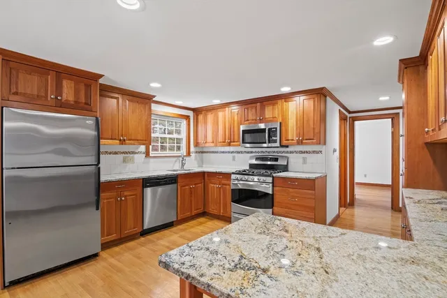 a kitchen with stainless steel appliances kitchen island granite countertop a refrigerator stove top oven and sink