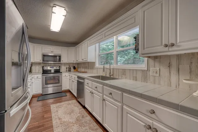 a kitchen with granite countertop white cabinets and stainless steel appliances