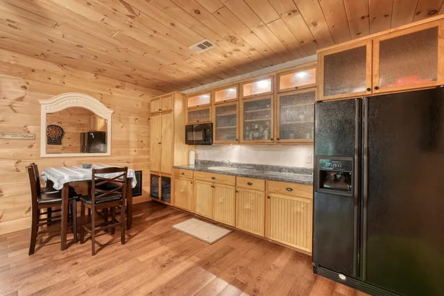 a kitchen with stainless steel appliances granite countertop a refrigerator a stove and a dining table with wooden floors