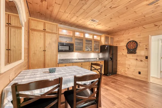 a kitchen with stainless steel appliances granite countertop a table chairs and wooden cabinets