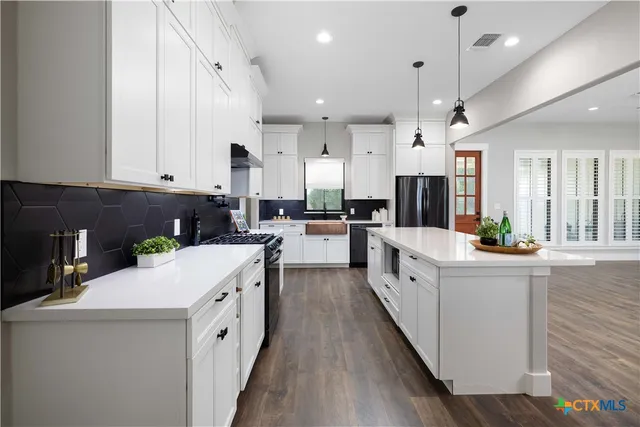 a large kitchen with stainless steel appliances kitchen island a large counter top and a stove