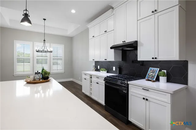 a kitchen with a stove and white cabinets