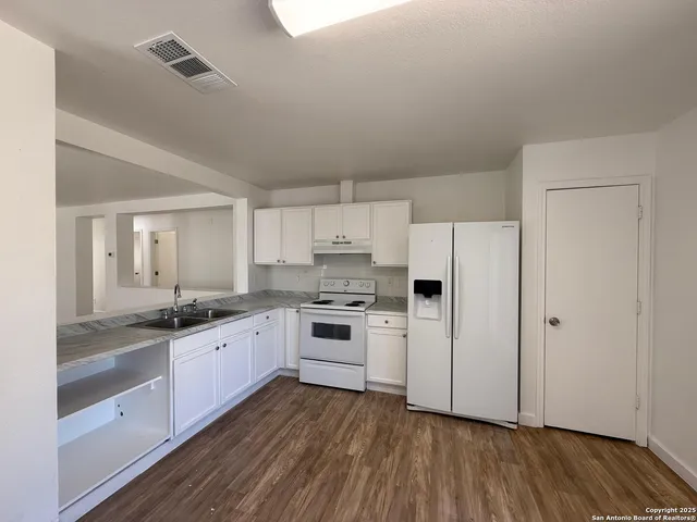 a kitchen with granite countertop a sink cabinets and stainless steel appliances