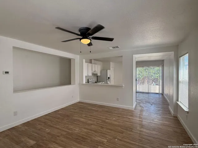 a view of empty room with wooden floor and fan