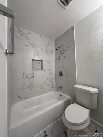 a white toilet sitting next to a bath tub and a shower