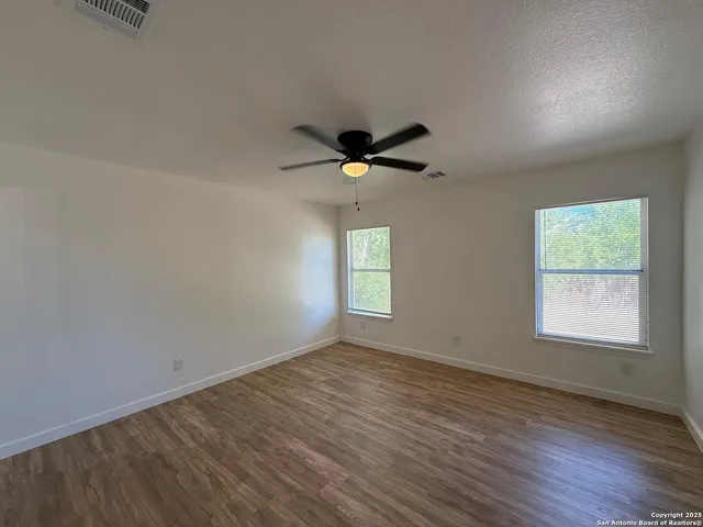 an empty room with wooden floor and windows