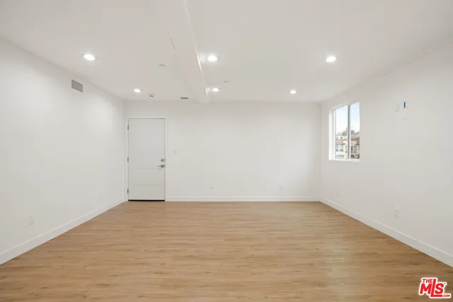 an empty room with wooden floor and window