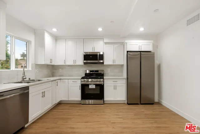 a kitchen with stainless steel appliances granite countertop a refrigerator a sink a stove a microwave and island