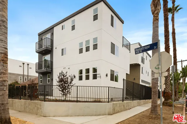 a view of a white building among the street with palm trees
