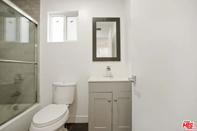 a bathroom with a toilet a sink a mirror and a shower