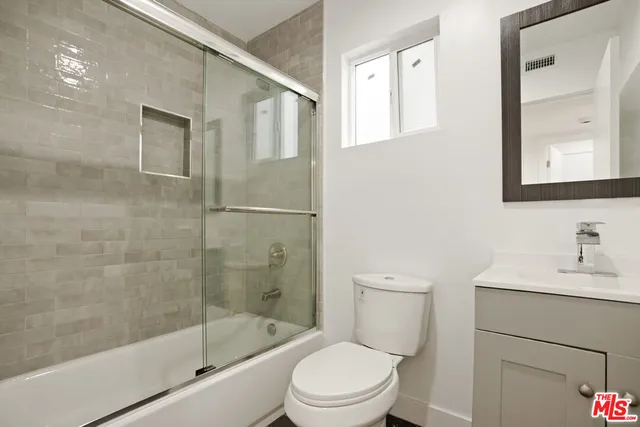 a bathroom with a bathtub shower sink mirror and toilet