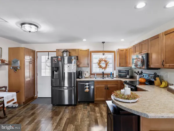 a kitchen with stainless steel appliances granite countertop a refrigerator a stove and a sink with wooden floor