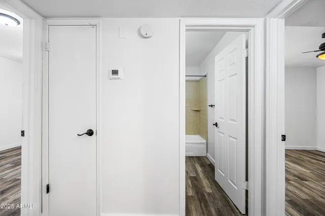 a view of empty room with wooden floor and fan