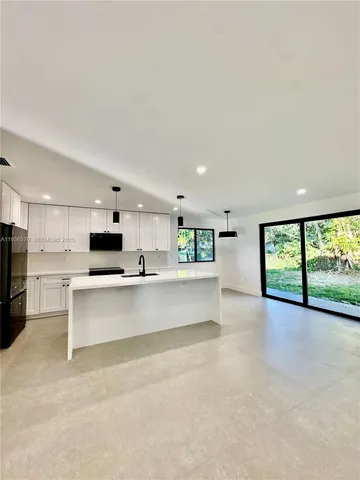 a large white kitchen with stainless steel appliances kitchen island a large counter top a stove and a sink