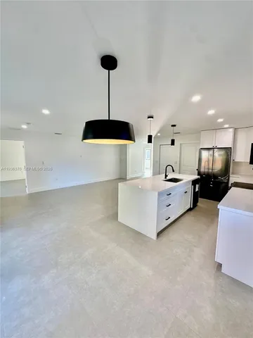 a large white kitchen with stainless steel appliances kitchen island a large counter top a stove and a refrigerator
