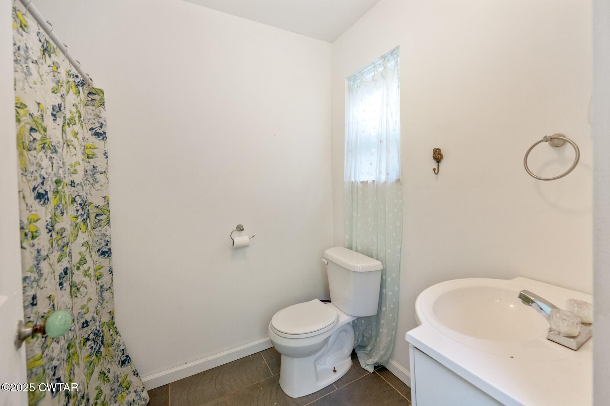 1035 Beacon Road Parsons, TN 38363 - Photo 29 of 70 a white toilet sitting next to a white sink and vanity