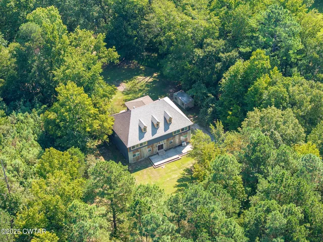 an aerial view of a house with a yard and large trees