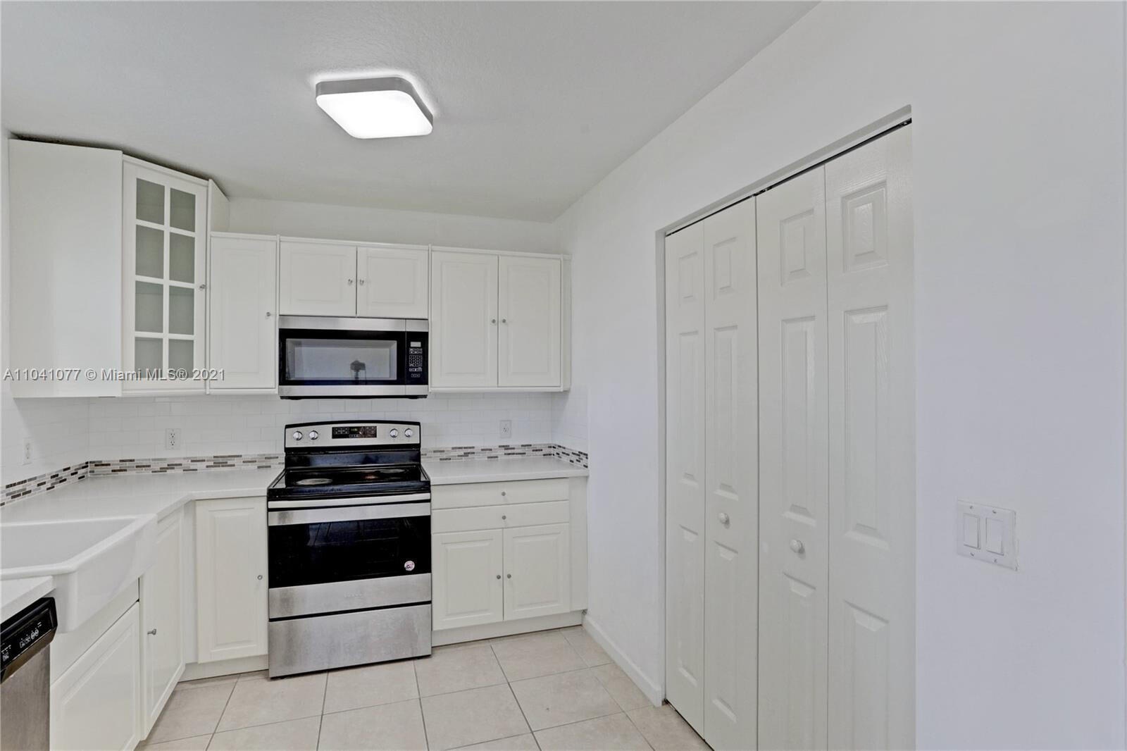 3810 North Jog Road, Unit 106 West Palm Beach, FL 33411 - Photo 2 of 13 a kitchen with white cabinets and white appliances