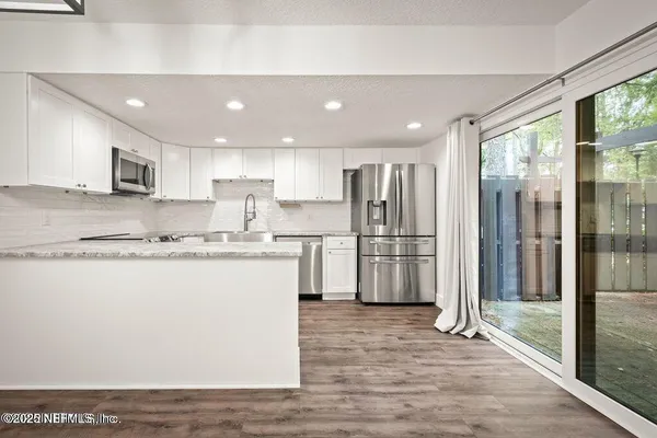 a large kitchen with stainless steel appliances granite countertop a refrigerator a sink and a stove