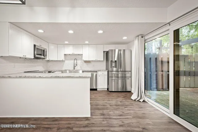 a large kitchen with stainless steel appliances granite countertop a refrigerator a sink and a stove