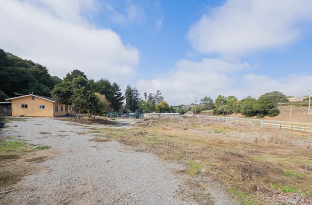 a view of a dry yard with wooden fence
