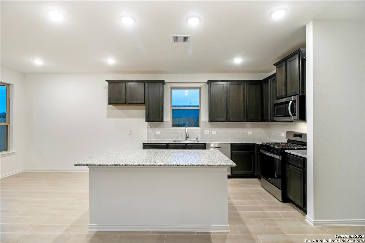 a large kitchen with granite countertop lots of counter space and stainless steel appliances