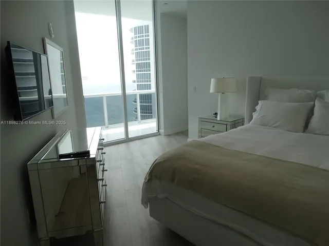 a bedroom with a bed and a flat tv screen next to a window