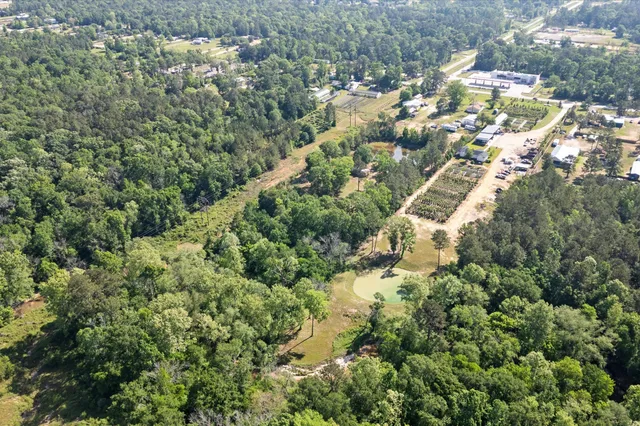 an aerial view of residential house with outdoor space and trees all around
