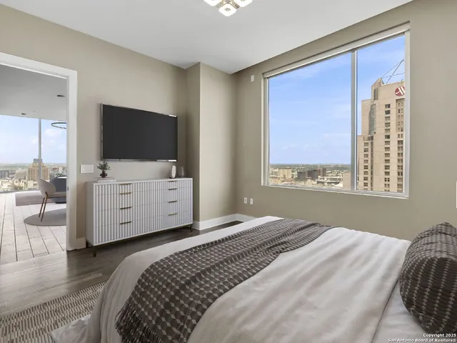 a bedroom with a large bed and a flat tv screen on dresser