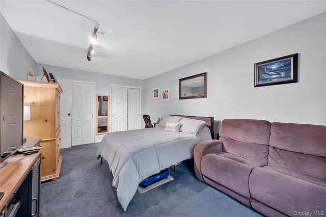 a bedroom with a bed couch and mirror