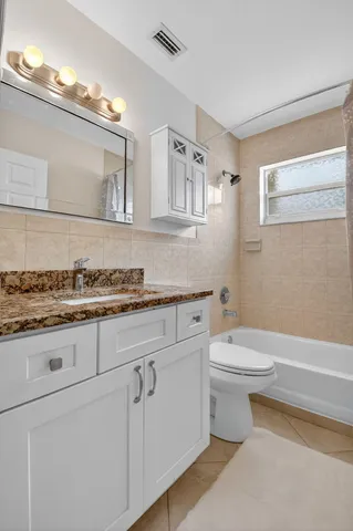a bathroom with a granite countertop toilet a sink and a mirror