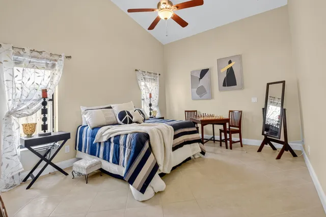 a spacious bedroom with a bed a desk and chair with the large mirror