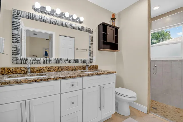 a bathroom with a granite countertop toilet sink and mirror