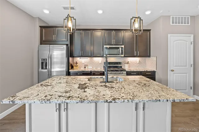 a kitchen with kitchen island granite countertop a stove and a sink