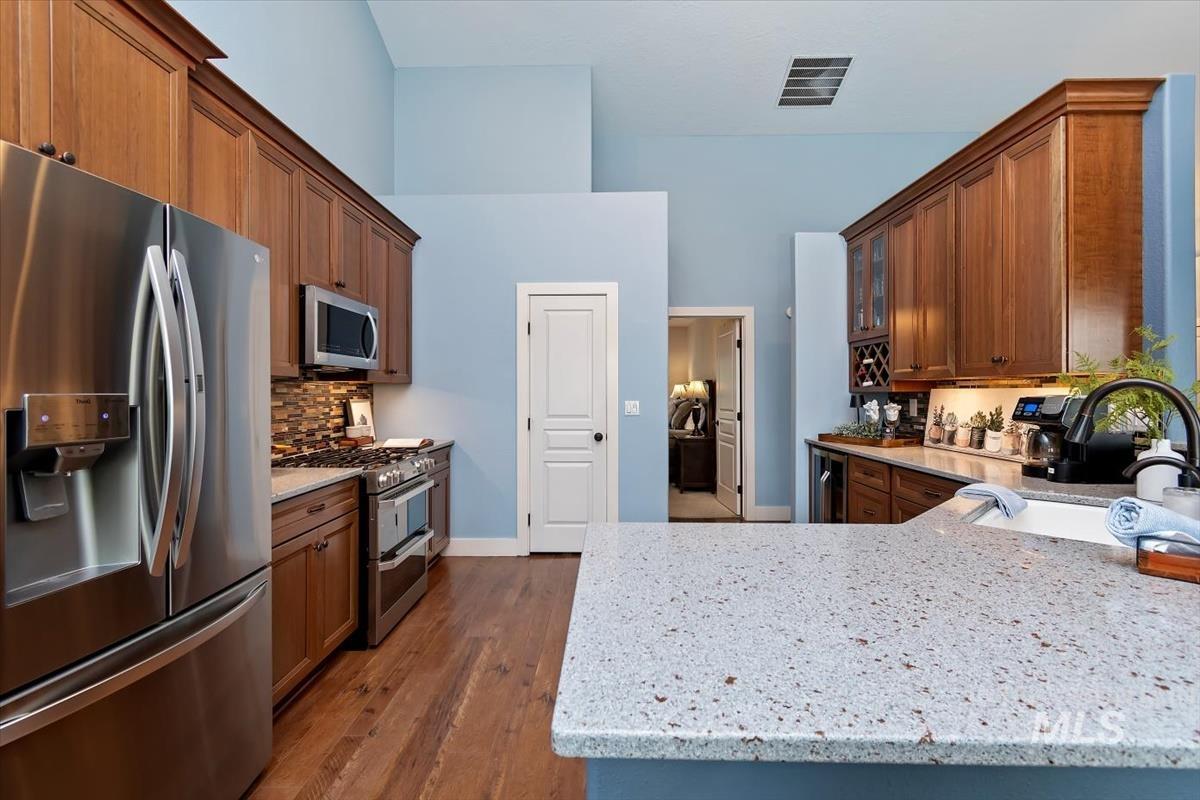 10462 West Lanktree Gulch Road Star, ID 83669 - Photo 14 of 48 Kitchen featuring rich wood cabinetry, stainless steel appliances, a tiled backsplash, and a light-colored speckled countertop