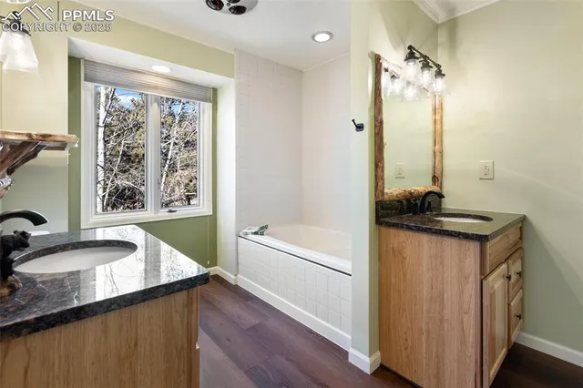 a bathroom with a granite countertop sink a bathtub and a window