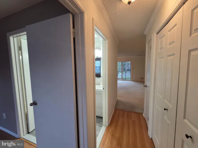 a view of a hallway with wooden floor and a bathroom