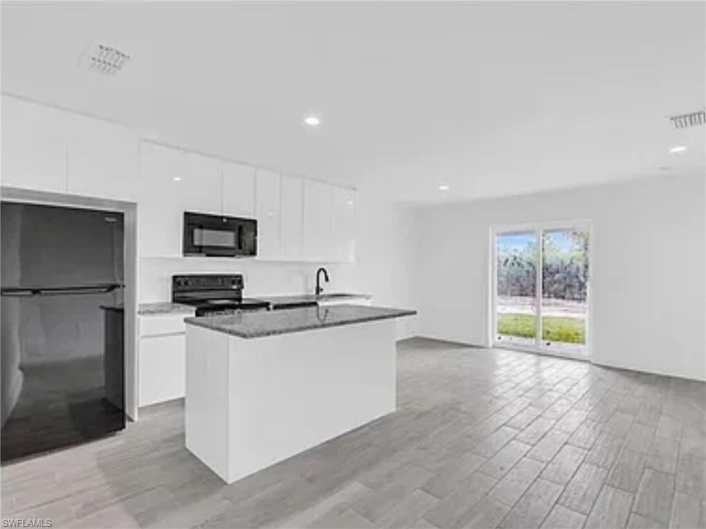 3120 Peters Avenue Naples, FL 34112 - Photo 5 of 12 a kitchen with stainless steel appliances a stove a sink and a microwave