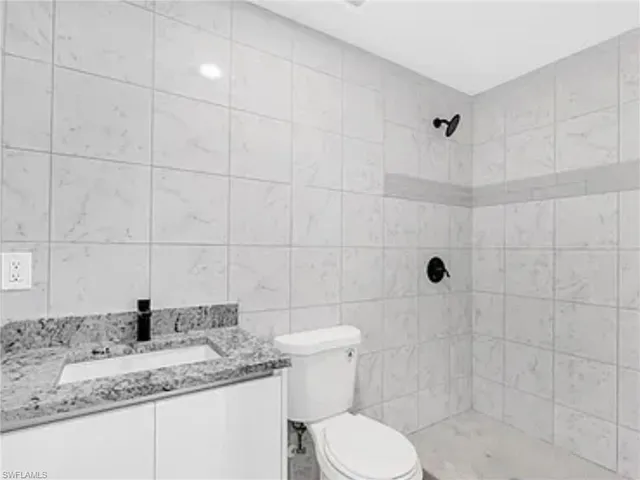 a bathroom with a granite countertop sink a toilet and shower