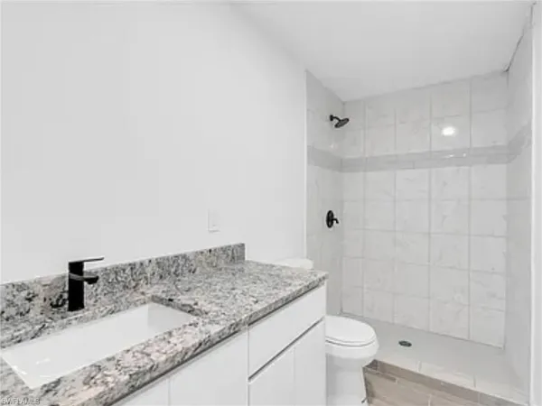 a bathroom with a granite countertop sink a toilet and shower