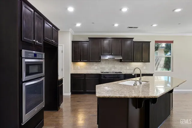 a kitchen with kitchen island granite countertop a sink stainless steel appliances and cabinets