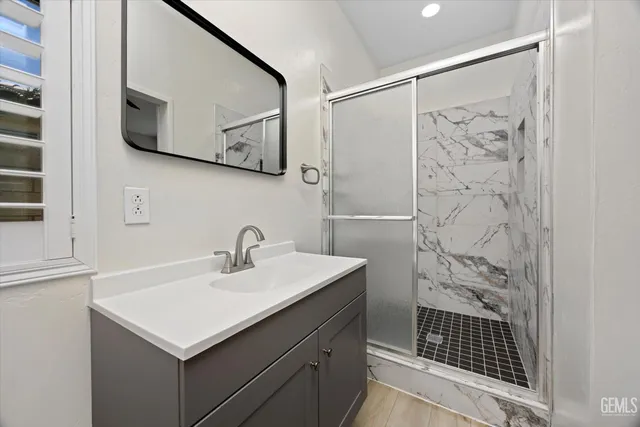 a bathroom with a sink vanity and a shower