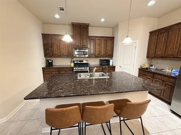 a kitchen with kitchen island granite countertop a table chairs sink and microwave
