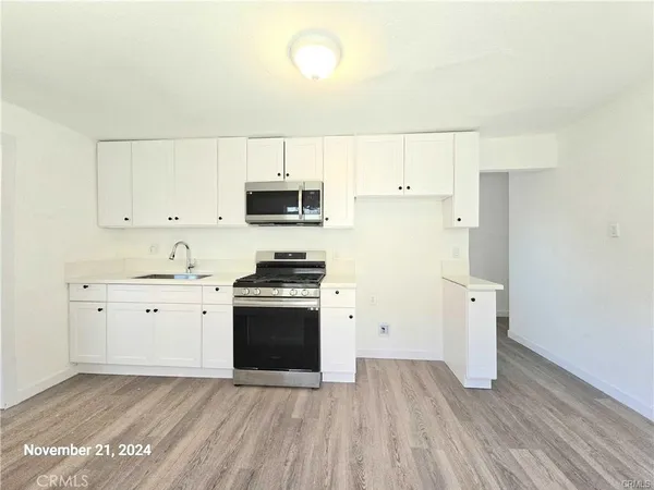 a kitchen with cabinets appliances wooden floor and a window