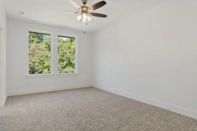 an empty room with a window and a fan